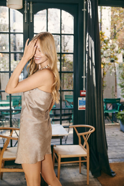 Woman in beige silk mini dress at a bar